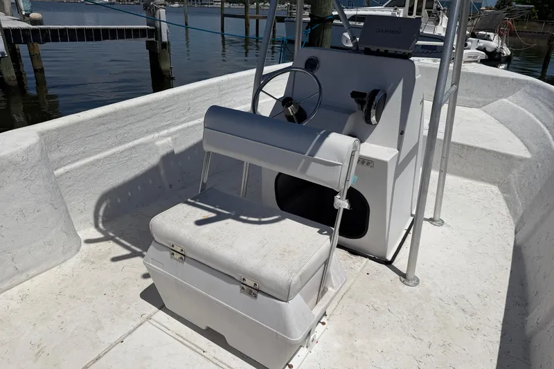 Slide: The Image of 2002 Sea Chaser 2100 CC boat interior with steering console and seating, docked by the water. - 18