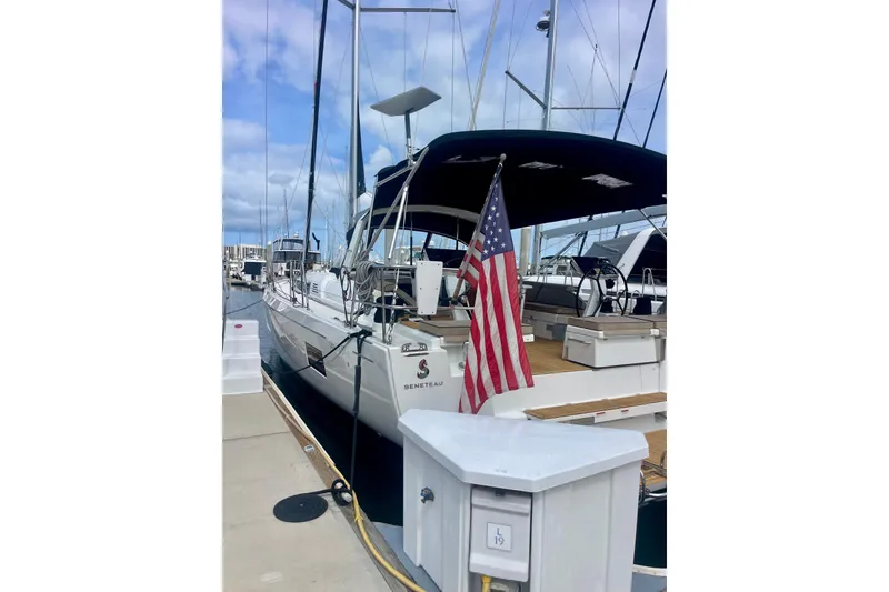Slide: The Image of 2023 Beneteau Oceanis 51.1 yacht docked with American flag displayed. - 2