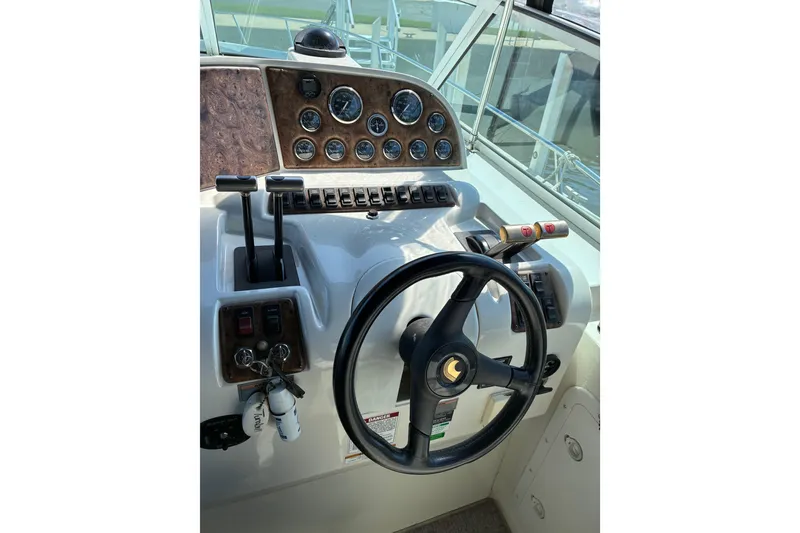 Slide: The Image of Cockpit of a 1999 Trojan 360 Express boat with steering wheel and control panel. - 12