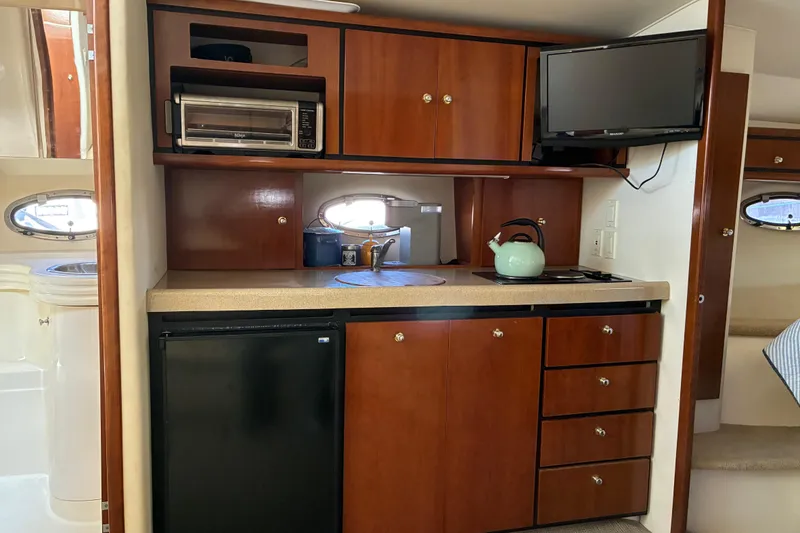 Slide: The Image of 1999 Trojan 360 Express yacht kitchen with wooden cabinets, appliances, and a compact design. - 17