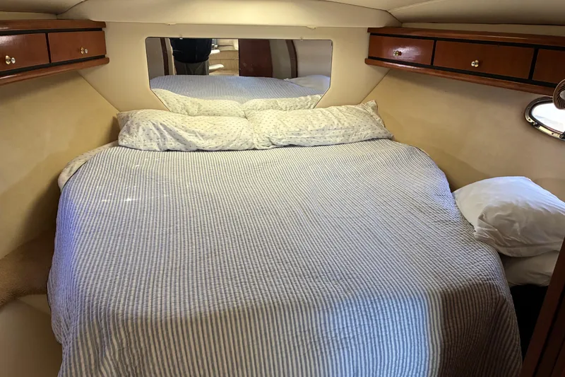 Slide: The Image of Cozy cabin bedroom in 1999 Trojan 360 Express yacht with striped bedding and wooden cabinets. - 23