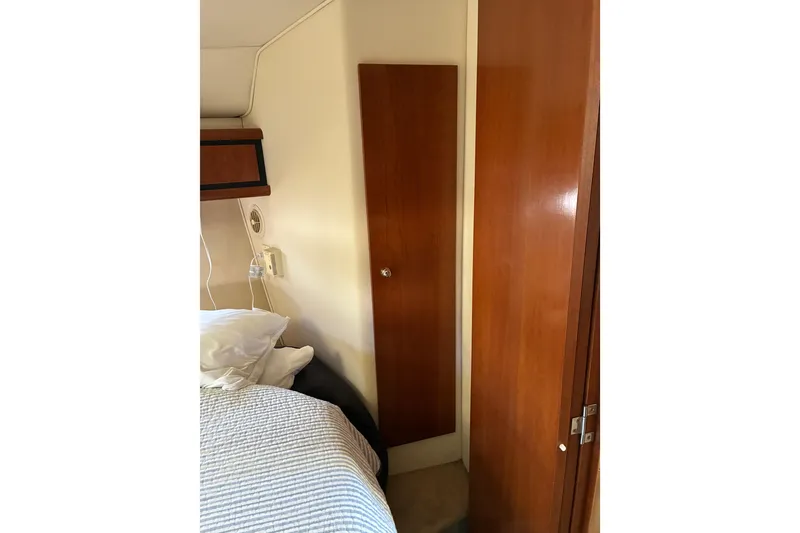 Slide: The Image of Interior of 1999 Trojan 360 Express boat with wooden cabinetry and cozy bedding. - 24