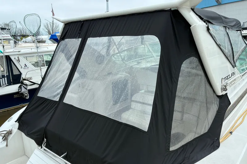 Slide: The Image of 1999 Trojan 360 Express boat with black canvas cover in marina setting. - 5