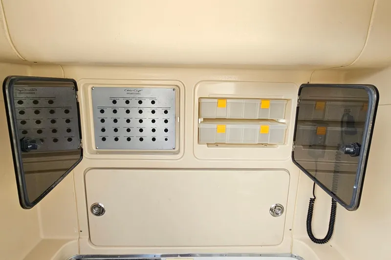 Slide: The Image of 2008 Chris-Craft Catalina 29 electrical panel with storage compartments and control switches. - 14