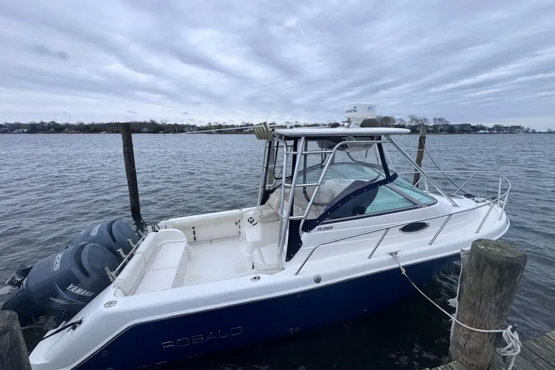 The Image of 2003 Robalo R265 Walkaround boat docked by the water on a cloudy day. - 0