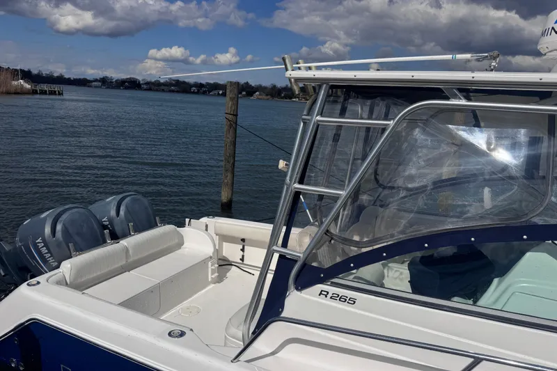 Slide: The Image of 2003 Robalo R265 Walkaround boat with Yamaha engines docked by a serene lake. - 3