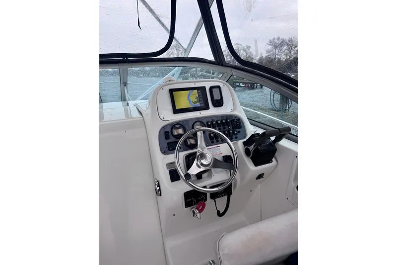 Slide: The Image of 2003 Robalo R265 Walkaround boat helm with steering wheel and navigation controls. - 4