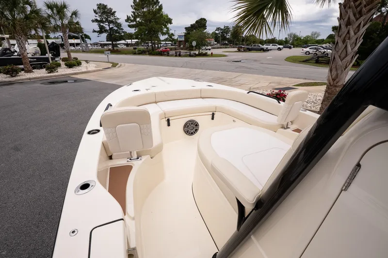 Slide: The Image of 2026 Scout 231 XSB boat interior with seating and cup holders, parked near palm trees. - 15