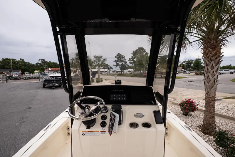 Slide: The Image of 2026 Scout 231 XSB boat dashboard with steering wheel and controls, parked near palm trees. - 8