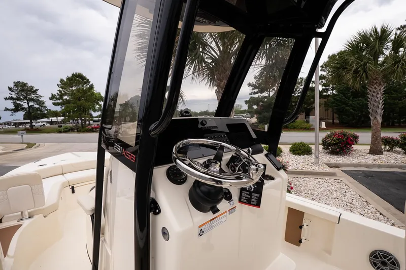 Slide: The Image of 2026 Scout 231 XSB boat cockpit with steering wheel and console, surrounded by palm trees. - 9