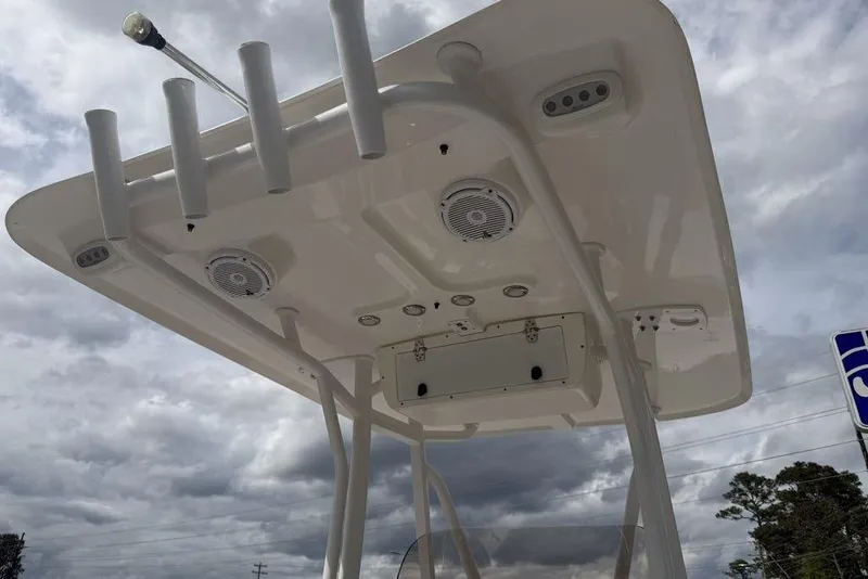 Slide: The Image of 2018 Sea Hunt Ultra 225 boat T-top with rod holders and speakers under cloudy sky. - 13