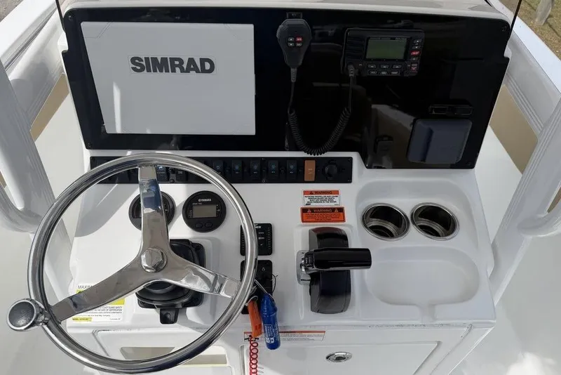 Slide: The Image of 2018 Sea Hunt Ultra 225 boat dashboard with steering wheel, Simrad display, and control panel. - 14