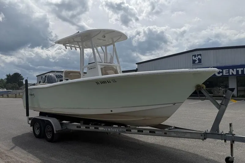 Slide: The Image of 2018 Sea Hunt Ultra 225 boat on trailer, parked outside a showroom under cloudy skies. - 5