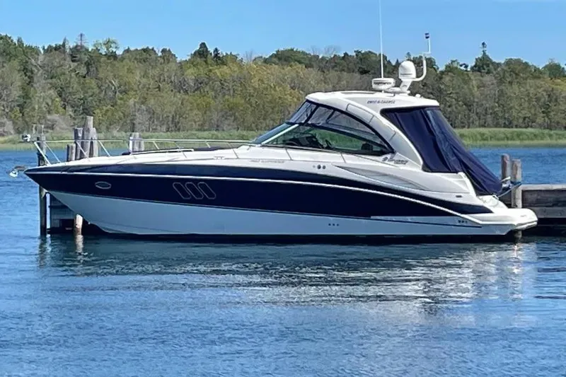 The Image of 2012 Cruisers Yachts 380 Express docked on a serene lake with lush greenery. - 0