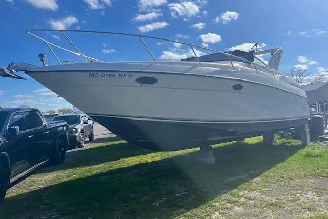 The Image of 1997 Regal Commodore 322 boat on land, sunny day, parked beside vehicles. - 0