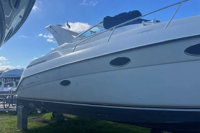 Slide: The Image of 1997 Regal Commodore 322 boat on blocks, side view under blue sky. - 2