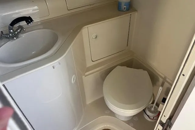 Slide: The Image of Compact bathroom in a 1997 Regal Commodore 322 boat, featuring a sink and toilet. - 20