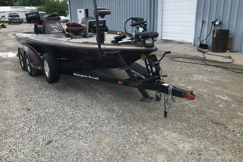 Slide: The Image of 2001 Ranger 518DVX Comanche boat on trailer, parked on gravel near a metal building. - 15