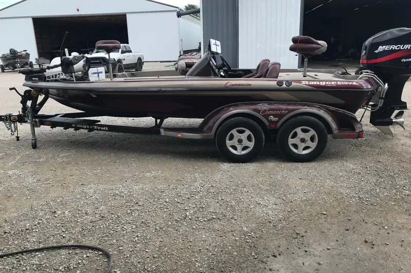 The Image of 2001 Ranger 518DVX Comanche boat on trailer, parked outside a garage. - 2