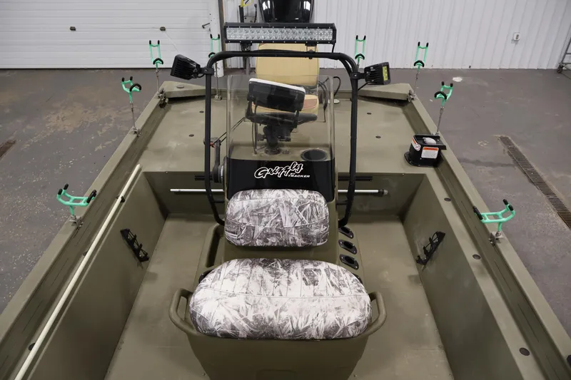 Slide: The Image of 2023 Tracker Grizzly 1860 MVX CC boat interior with camo seats and fishing rod holders. - 18