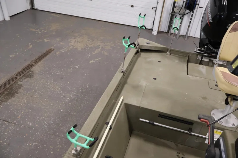 Slide: The Image of 2023 Tracker Grizzly 1860 MVX CC boat interior with rod holders in a garage setting. - 30
