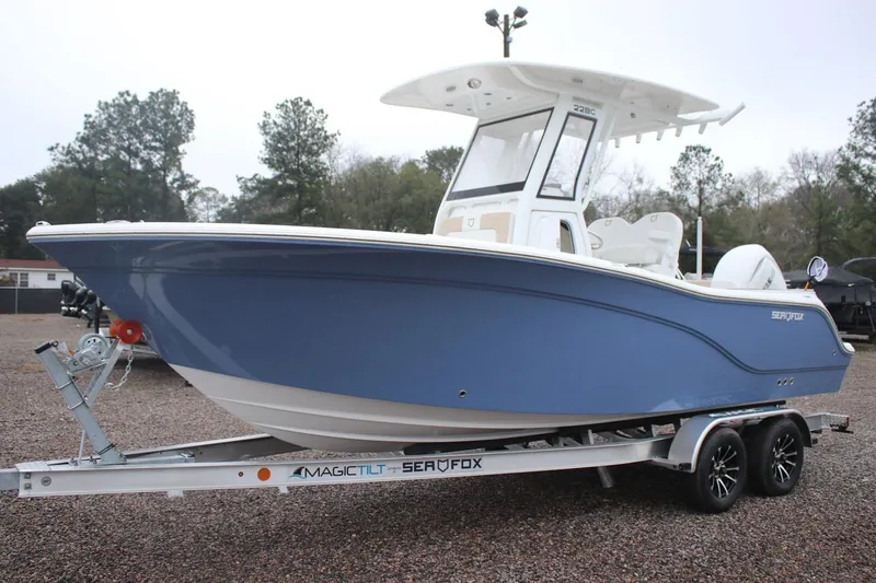 The Image of 2026 Sea Fox 228 Commander boat on trailer, blue hull, parked outdoors. - 0