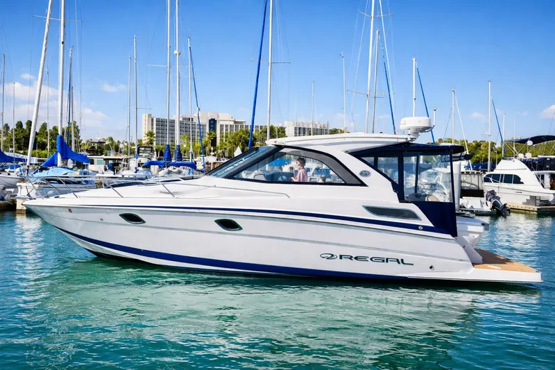 The Image of 2017 Regal 35 Sport Coupe yacht docked in marina, surrounded by sailboats. - 0