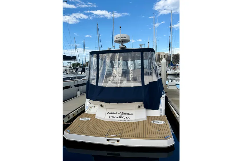 Slide: The Image of 2017 Regal 35 Sport Coupe docked at marina, featuring blue canopy and teak deck. - 10