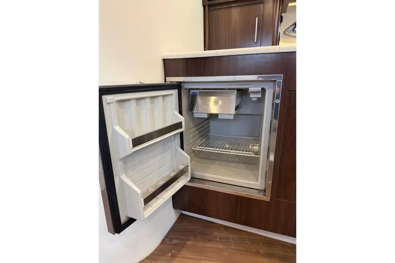 Slide: The Image of Open refrigerator in 2017 Regal 35 Sport Coupe yacht interior, featuring wooden cabinetry. - 12
