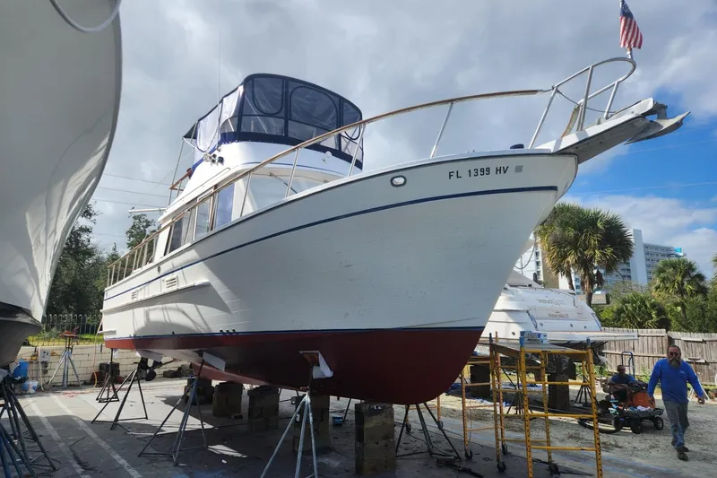 Slide: The Image of 1988 Overseas Monk 42 yacht docked at marina, clear sky, American flag waving. - 107