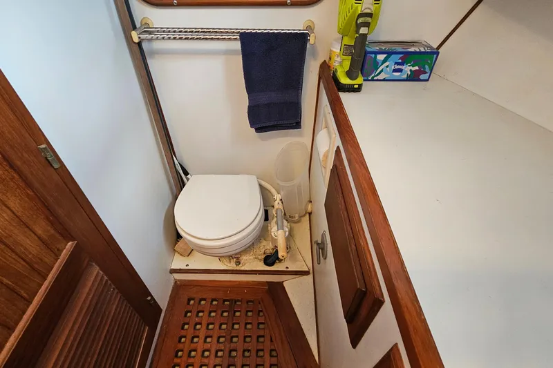Slide: The Image of 1988 Overseas Monk 42 boat bathroom with toilet, towel, and cleaning supplies. - 69