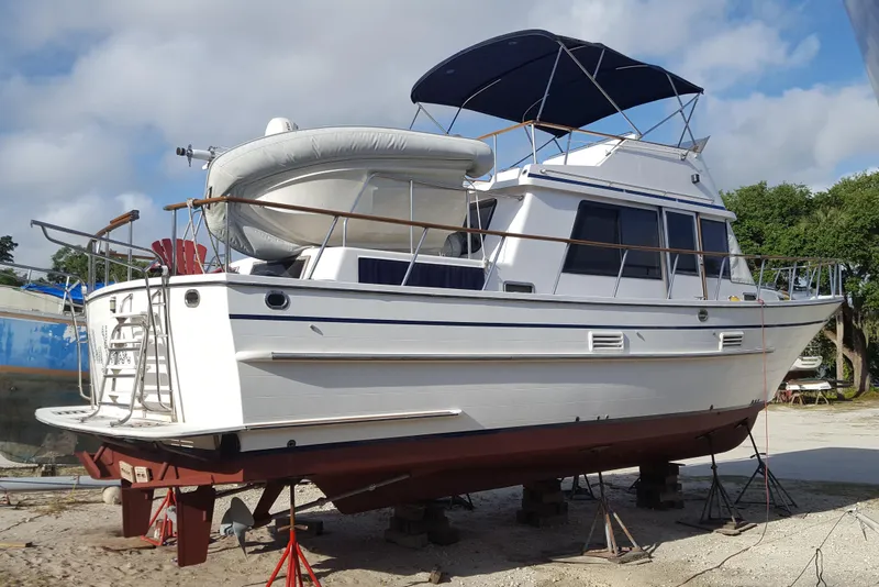 Slide: The Image of 1988 Overseas Monk 42 yacht on dry dock, featuring a white hull and blue canopy. - 105