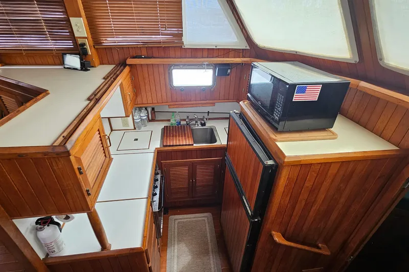 Slide: The Image of 1988 Overseas Monk 42 yacht kitchen with wood cabinetry, microwave, and compact appliances. - 32