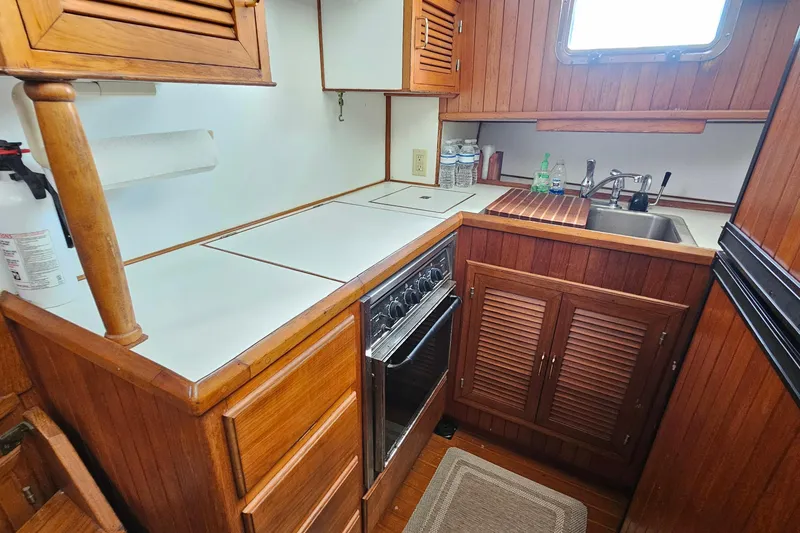 Slide: The Image of Compact wooden kitchen in 1988 Overseas Monk 42 boat, featuring stove, sink, and storage cabinets. - 34