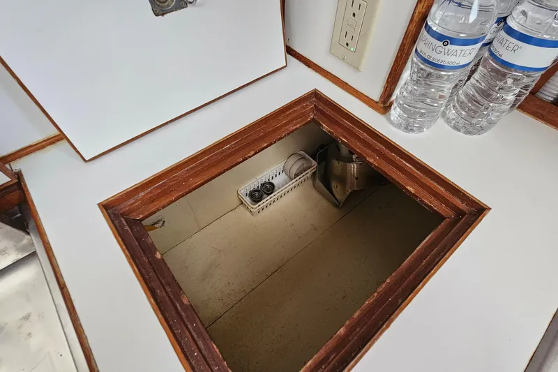 Slide: The Image of Open hatch on 1988 Overseas Monk 42 boat with storage space and water bottles nearby. - 42