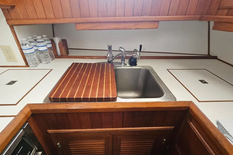 Slide: The Image of Compact kitchen area in a 1988 Overseas Monk 42 boat, featuring a sink and wooden countertop. - 43