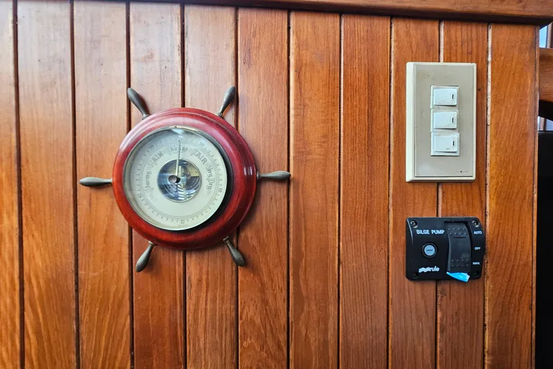 Slide: The Image of Wooden panel with barometer, switches, and bilge pump control on 1988 Overseas Monk 42. - 46
