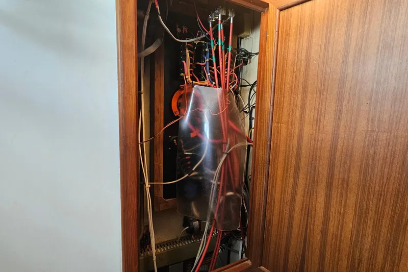 Slide: The Image of Electrical panel with wiring inside a wooden cabinet on a 1988 Overseas Monk 42. - 71