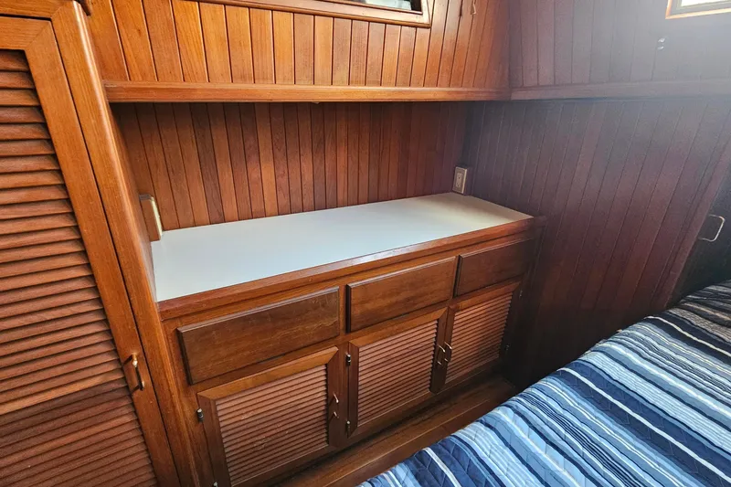 Slide: The Image of Wooden interior of 1988 Overseas Monk 42 yacht with built-in cabinets and striped bedding. - 84