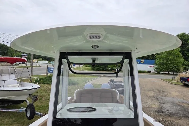 Slide: The Image of 2026 Sea Hunt Ultra 265 SE boat with T-top and seating, parked outdoors. - 15