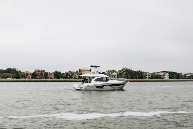 Slide: The Image of 2026 Beneteau Antares 11 Fly cruising near waterfront homes on a cloudy day. - 1