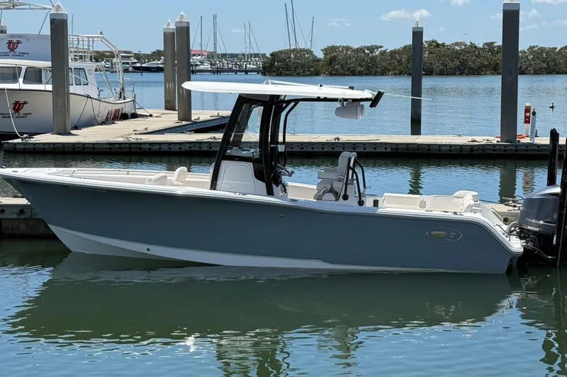 The Image of 2021 Sea Hunt Ultra 239 SE boat docked at marina, calm water, clear sky. - 0