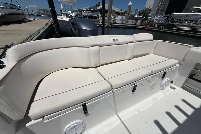 Slide: The Image of 2021 Sea Hunt Ultra 239 SE boat with white cushioned seating at a marina. - 10