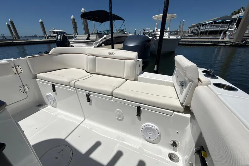 Slide: The Image of 2021 Sea Hunt Ultra 239 SE boat interior with cushioned seating at marina. - 11