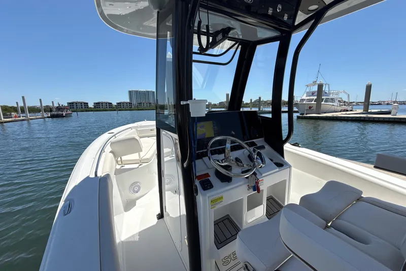 Slide: The Image of 2021 Sea Hunt Ultra 239 SE boat interior at marina, featuring steering console and seating. - 17