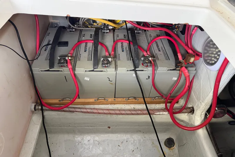 Slide: The Image of Battery compartment of a 2017 Edgewater 368CC boat with red cables and four batteries. - 14