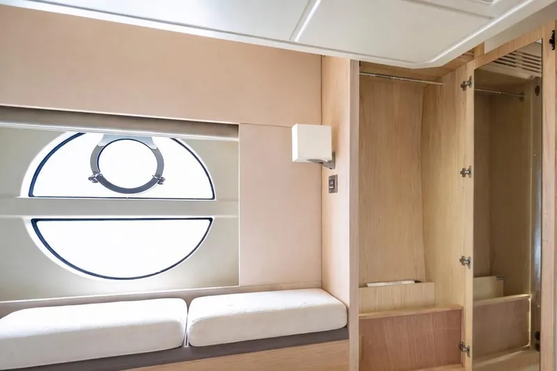 Slide: The Image of Interior of 2016 Beneteau Monte Carlo 5 yacht with circular window and wooden cabinetry. - 9