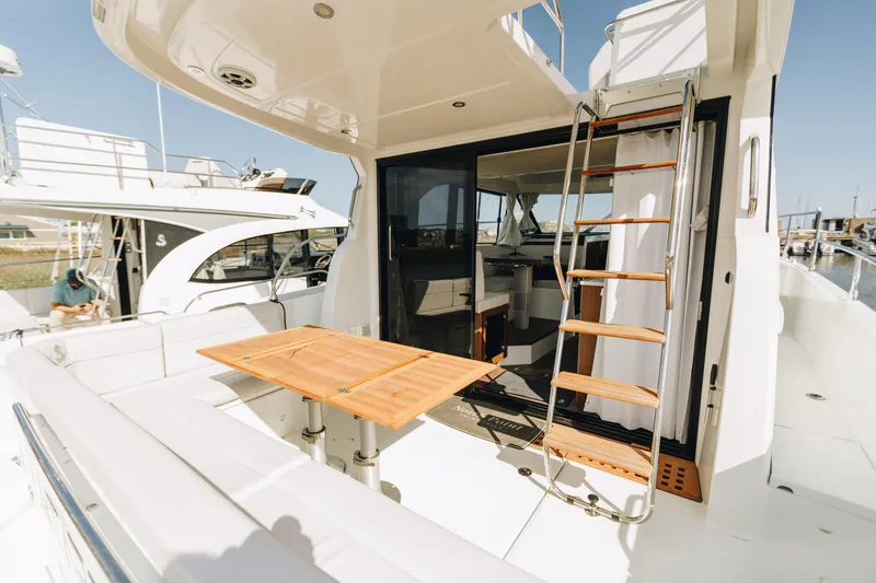 Slide: The Image of 2026 Beneteau Antares 12 Fly yacht with outdoor seating and ladder to upper deck. - 9