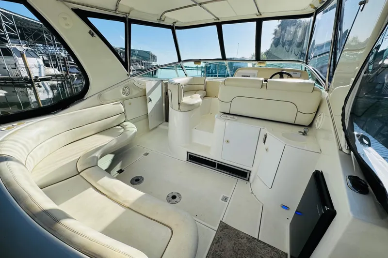 Slide: The Image of 2000 Cruisers Yachts 3575 Express interior with white seating and helm, docked at marina. - 21