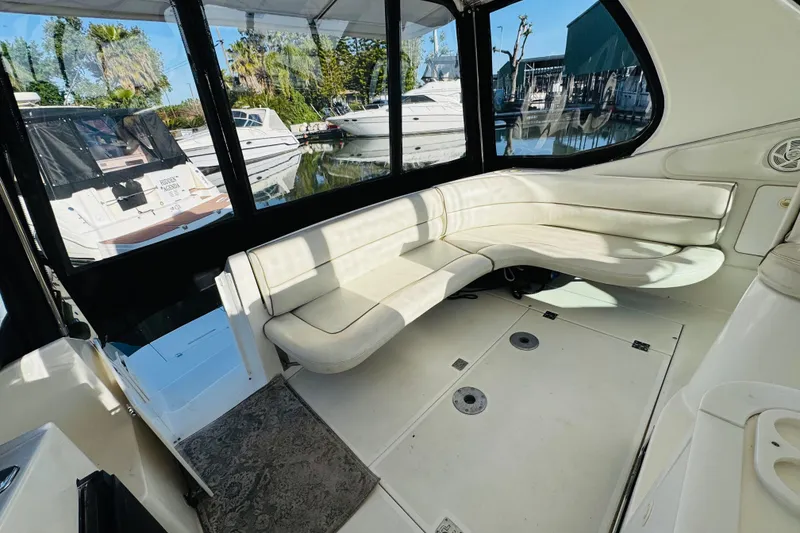 Slide: The Image of 2000 Cruisers Yachts 3575 Express interior with white seating and marina view. - 29